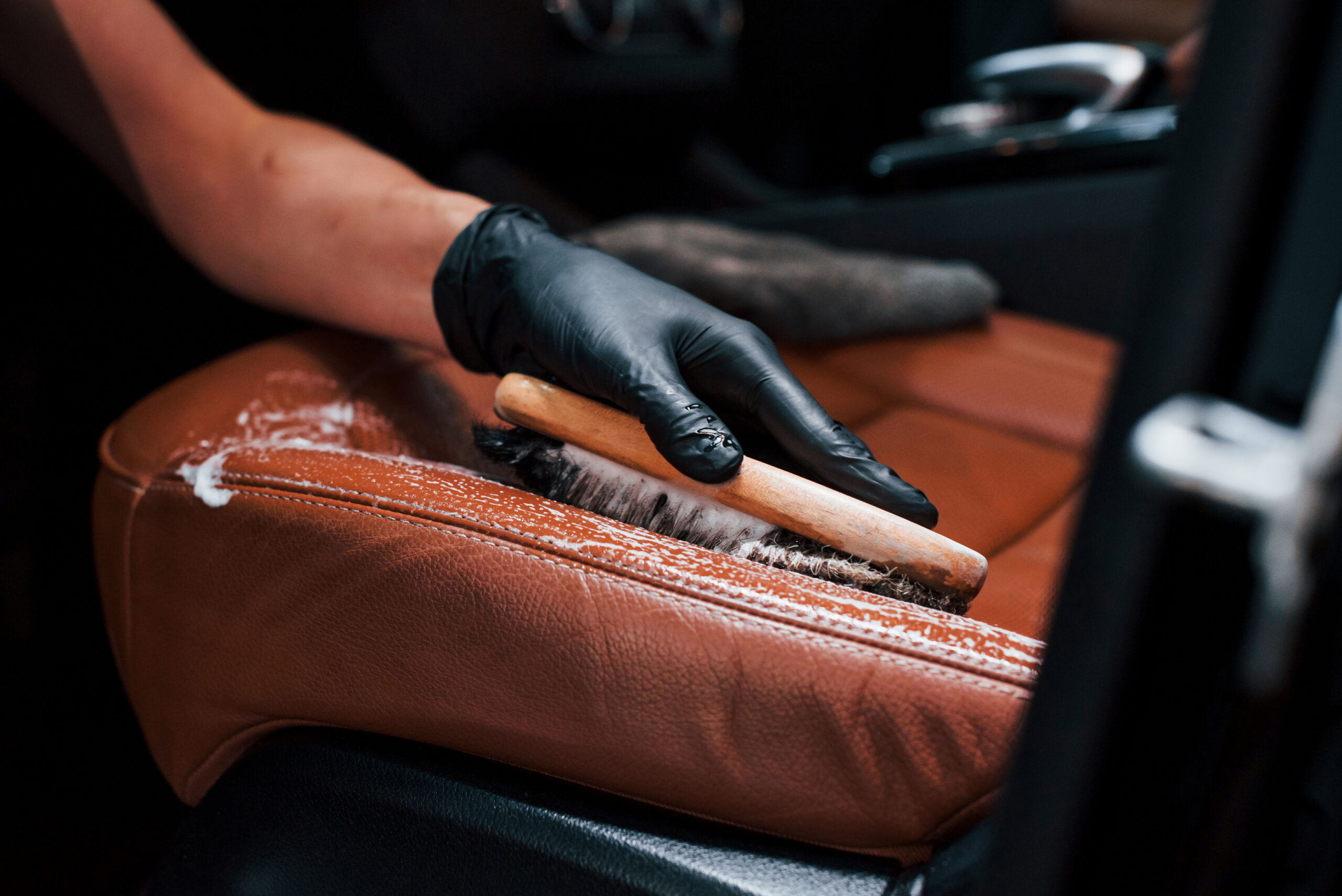 taking care about brown colored seats. modern black automobile get cleaned by woman inside of car wash station